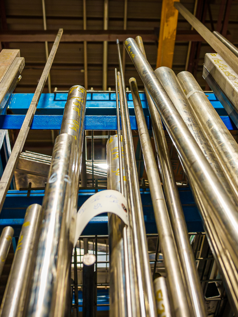 Metal pipes stored vertically in a rack, with industrial background Metal pipes stored vertically in a rack, with industrial background